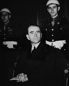 再rt Speer at the Nuremberg trial: Black and white photo of Speer and two guards in the background